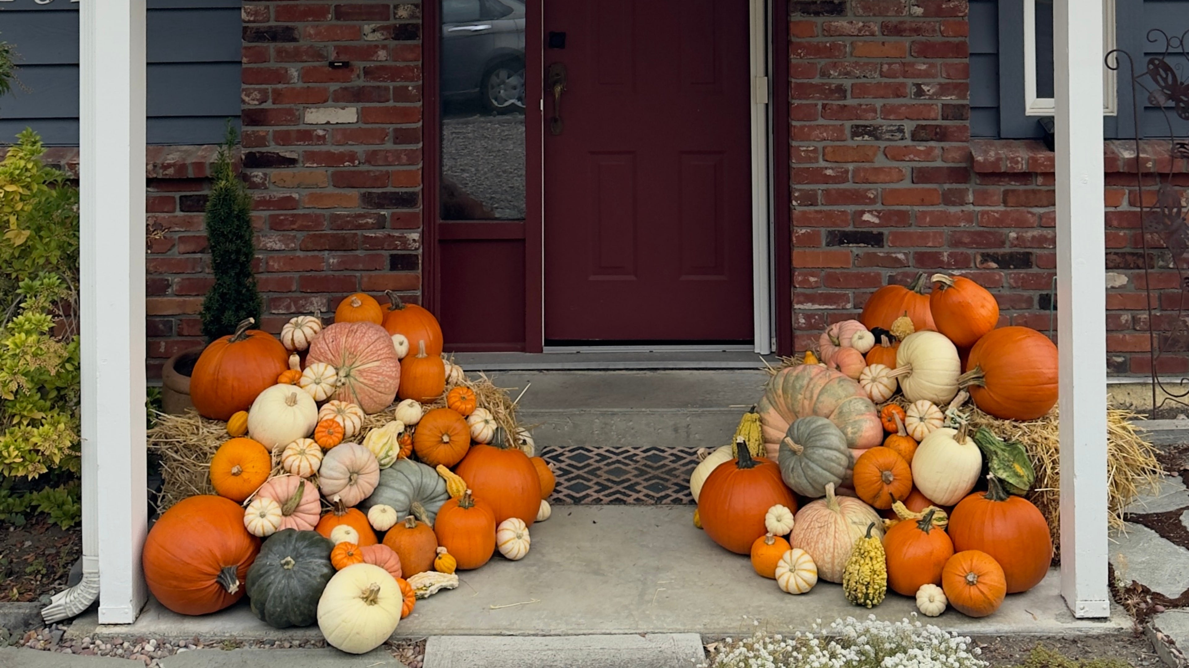Decorative arrangement of pumpkins on a front porch with a red door.