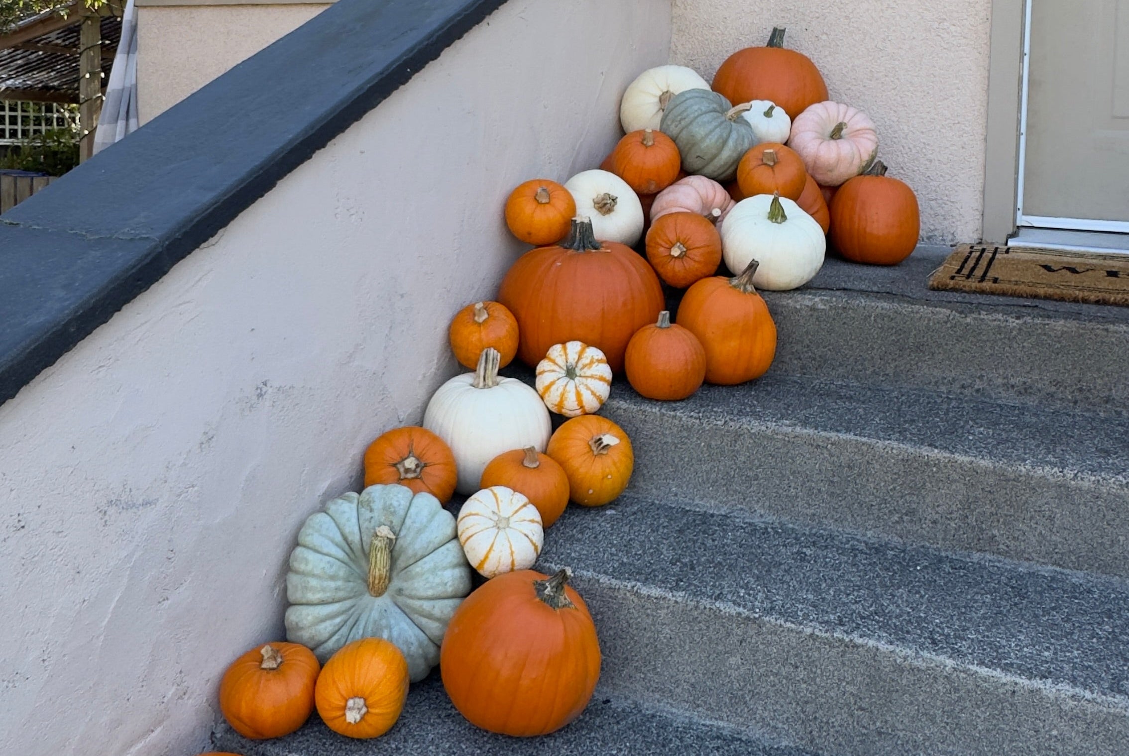 Decorative arrangement of pumpkins on a set of stairs in front of a house.