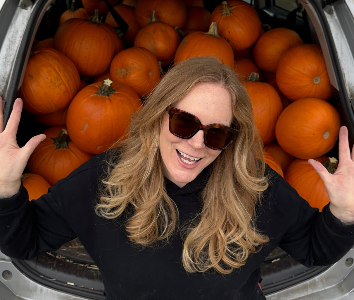 Person standing next to an open car trunk filled with pumpkins