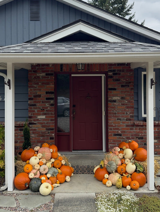 Decorative pumpkins in front of a house with a gray roof and white columns.