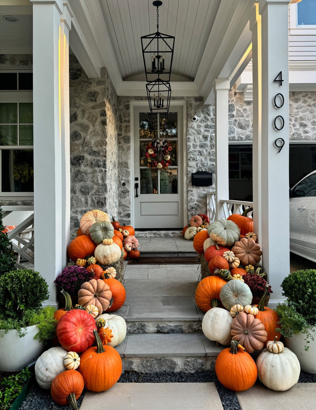 Decorative arrangement of pumpkins and gourds on a front porch.
