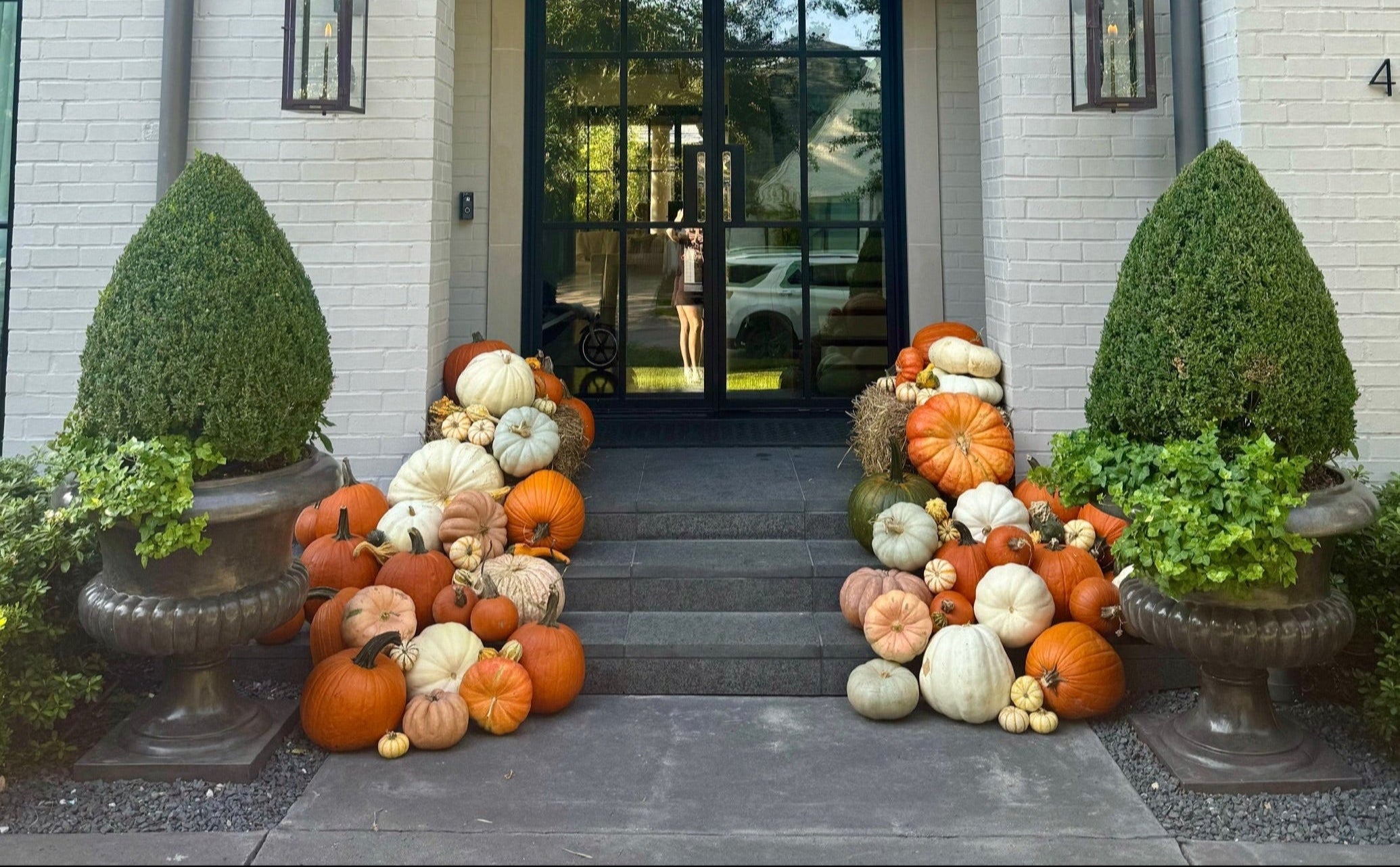 Decorative pumpkins and topiaries in front of a house entrance
