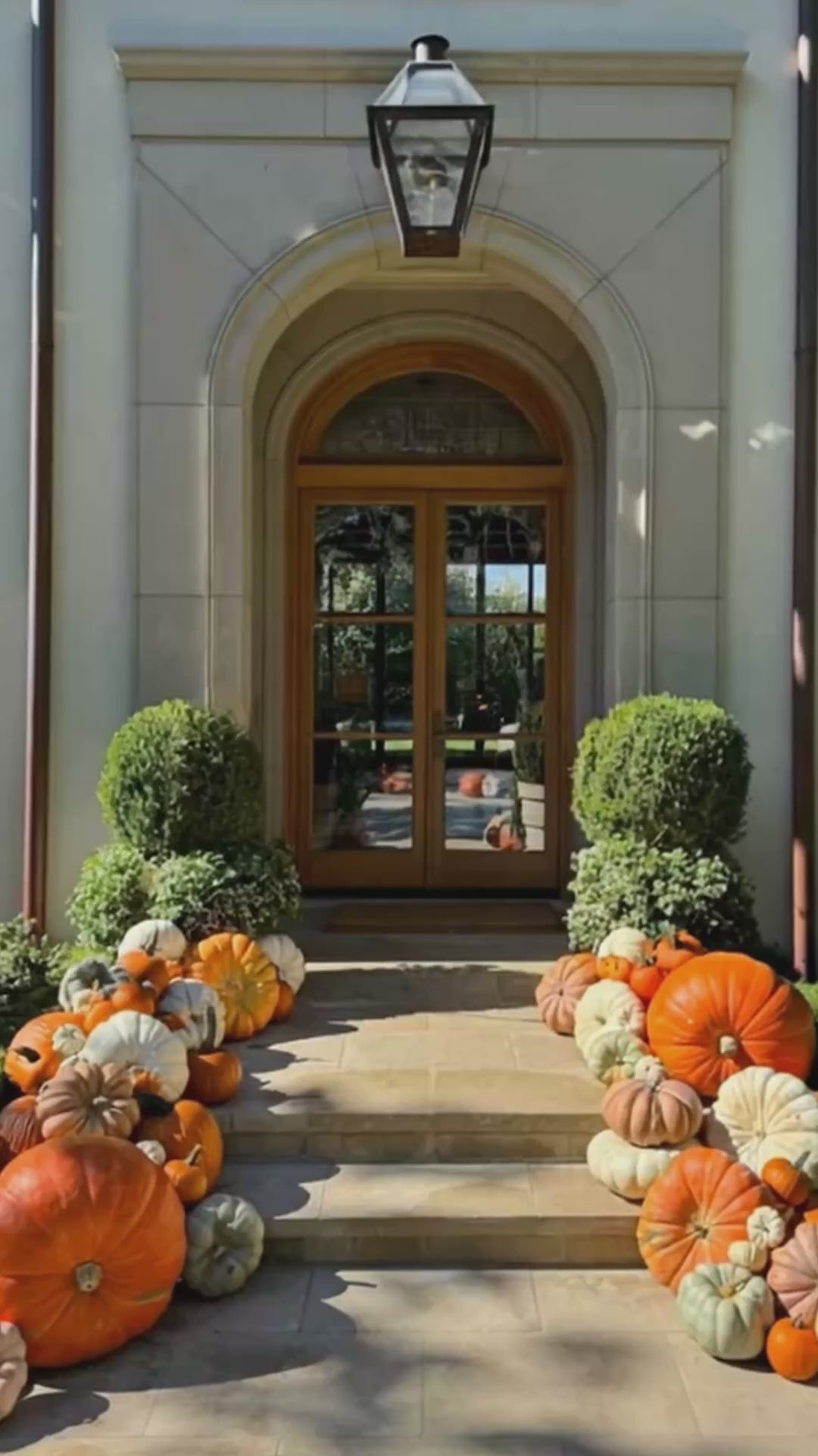 A video of a porch decorated with a variety of pumpkins in different shapes and sizes. 